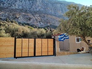 A gated property with a wooden fence, a small building with a blue and white striped flag, and a tree with a swing. - Elena Arginonta Beach House: 1st-floor apartment with ocean view (Arginonta)