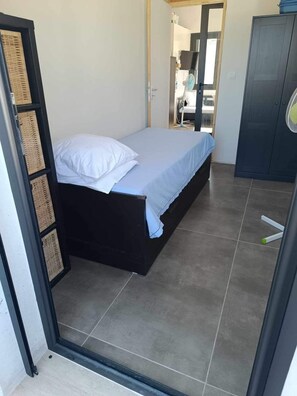Une chambre à coucher comprenant un lit, une armoire et une porte donnant sur une autre pièce.