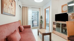 Ett vardagsrum med en soffa, ett soffbord, en tv och ett skåp.