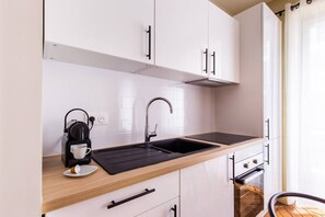 A modern kitchen with white cabinets, a black countertop, a sink, a coffee maker, and a window with curtains. - 2. Two bedrooms#Champs-Élysées#Arc de Triomphe#AC (Paris)