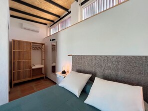 A bedroom with a bed, pillows, a nightstand, a mirror, a wardrobe, and a window. - House with a pool, 25 minutes from Seville, 3 suites, spacious outdoor area. (AN)