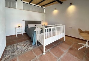A room with a crib, a bed, a small table, and a chair. - House with a pool, 25 minutes from Seville, 3 suites, spacious outdoor area. (AN)