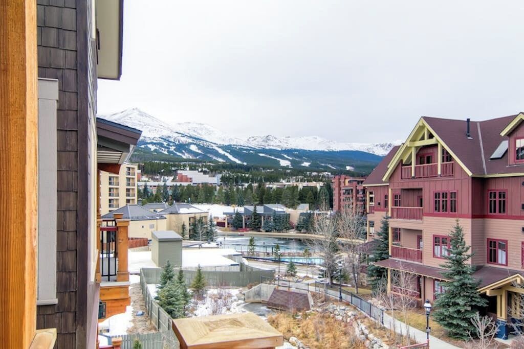 A multi-story building with a pool area, surrounded by snow-capped mountains.