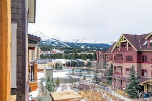 A multi-story building with a pool area, surrounded by snow-capped mountains. - Luxury condo with hot tubs & pool, walk to lifts & downtown Breckenridge (Breckenridge)