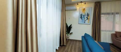 A room with a blue sofa, a potted plant, and a painting on the wall.