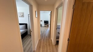 A hallway with a bed, a TV, and a sofa.