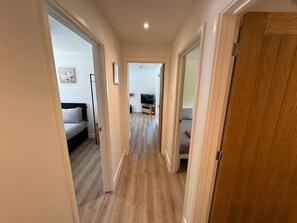 A hallway with a bed, a TV, and a sofa.