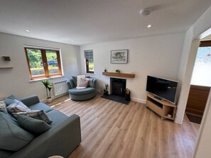 A living room with a sofa, a round chair, a fireplace, and a TV.