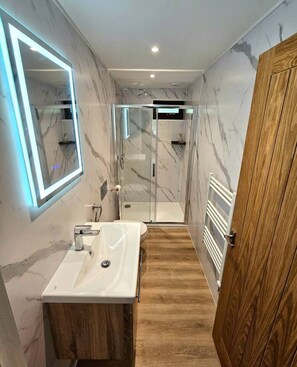Ein modernes Badezimmer mit Marmorwand, Duschkabine aus Glas und Holztür.