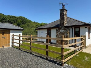 Ein rustikales Gebäude mit Schornstein, Holzzaun und Kiesweg.