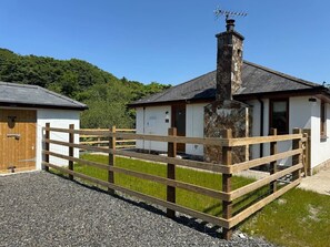Ein rustikales Gebäude mit einem Steinsschornstein, einem Holzzaun und einem Schotterweg.