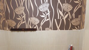 Un baño con inodoro, lavabo y un porta cepillos de dientes en la pared.
