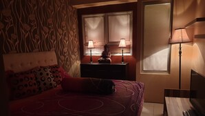 Un dormitorio con una cama, dos lámparas de noche, un aparador y una ventana.