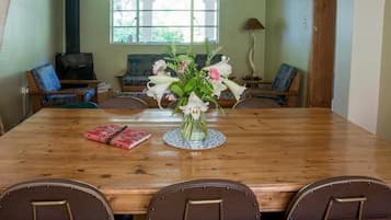 Una mesa de comedor de madera con un florero en el centro, rodeada de sillas.