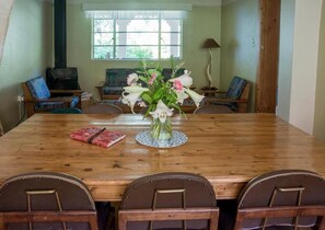 A wooden dining table with a vase of flowers in the center, surrounded by chairs.
