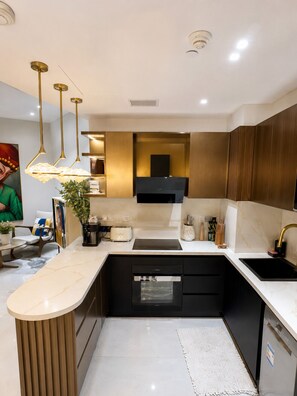 A modern kitchen with a central island, built-in appliances, and pendant lighting.