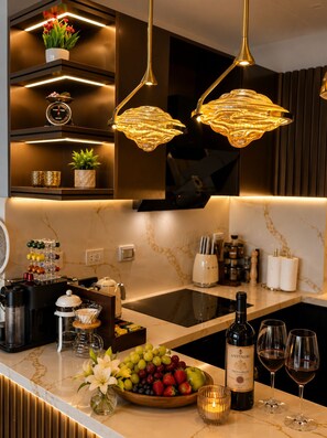 A modern kitchen with a marble countertop, a built-in stove, and overhead lighting fixtures.