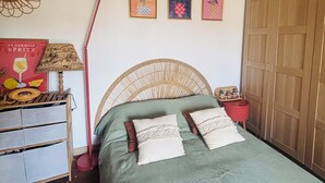 Une chambre à coucher avec un lit, une armoire, une lampe et des œuvres d’art murales.