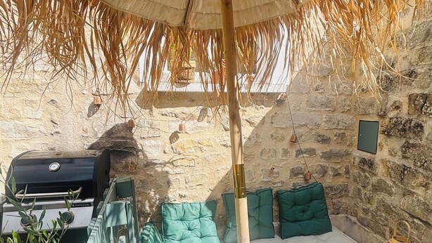 Une pièce rustique aux murs de pierre, avec un lit, un barbecue et un panier en osier.