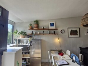 A compact kitchen with a refrigerator, a dining table with chairs, and a window providing natural light. - Stylish 1 BDR APT in the heart of Kilmainham (Dublin)
