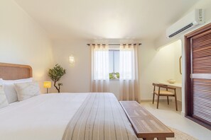 A hotel room with a bed, a small table, a chair, a lamp, and a window with curtains. - S o Rafael Apartment by Minhos Guest (Albufeira)