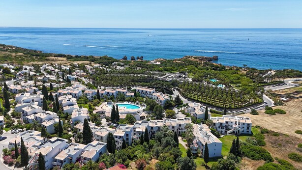 An aerial view of a coastal residential area with villas, a central swimming pool, and a view of the sea. - S o Rafael Apartment by Minhos Guest (Albufeira)