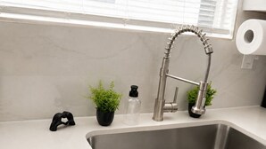 Una cocina moderna con un lavamanos de acero inoxidable, un grifo y un ventanal con persianas.
