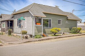 Ein eingeschossiges Haus mit Veranda, kleinem Garten und einem Straßenschild.