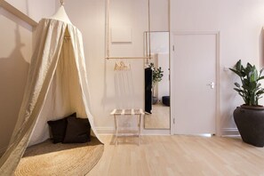 Ein Zimmer mit einem Baldachinbett, einem kleinen Tisch, einer Topfpflanze und einem Spiegel an der Wand.