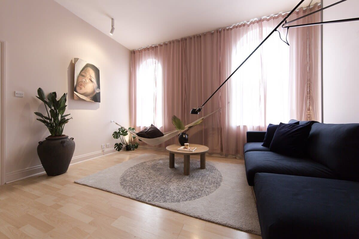 A living room with a sofa, a round coffee table, a hammock, and a potted plant.