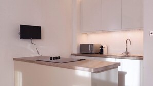 Eine moderne Küche mit Flachbildfernseher, Mikrowelle und Spüle.