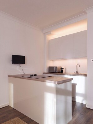 Eine moderne Küche mit Flachbildfernseher, Mikrowelle und Spüle.