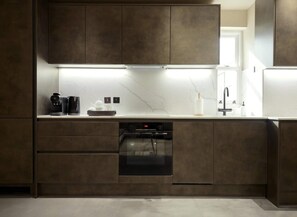 Une cuisine moderne dotée d’appareils électroménagers intégrés, d’un lave-vaisselle et d’un dosseret en marbre.