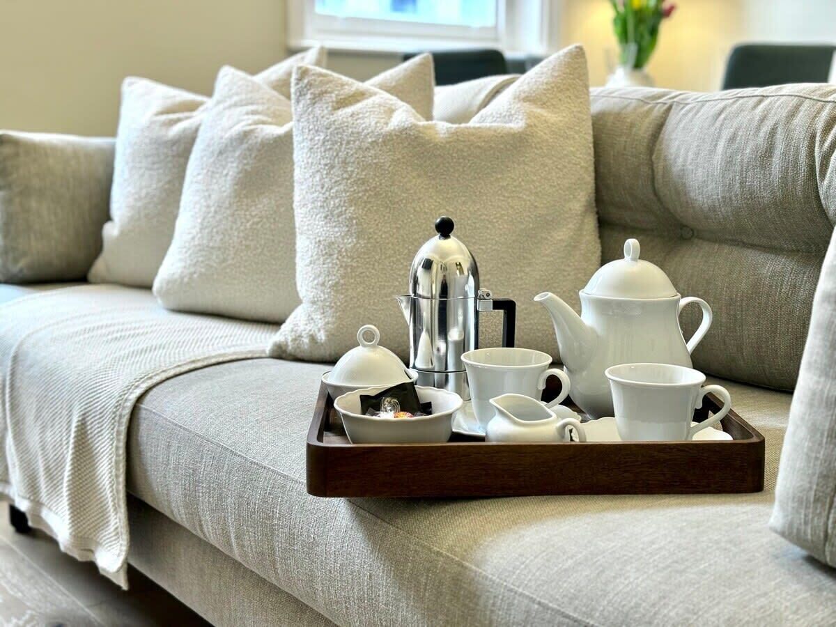A sofa with a tray of tea set and a coffee pot.