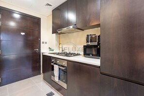 Eine moderne Küche mit einem dunkelholzartigen Schrank, einem eingebauten Backofen, einer Mikrowelle und einem Gasherd.