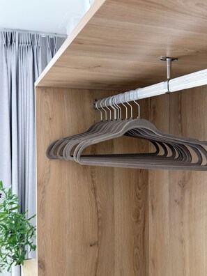 Ein Holzschrank mit Kleiderstange und einer Pflanze daneben.