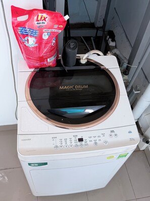 Une machine à laver à chargement frontal, dotée d’un tambour d’admission circulaire, d’un sac de lessive rouge et d’un tuyau noir.