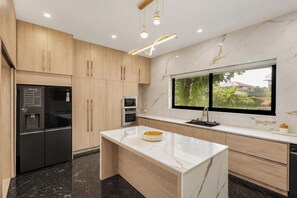 Una cocina moderna con una isla de mármol, electrodomésticos integrados y un amplio ventanal con vistas.