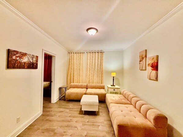 A living room with a sofa, ottoman, and a lamp.