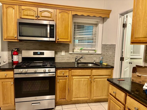 A kitchen with wooden cabinets, a stainless steel microwave, a gas stove, and a sink.