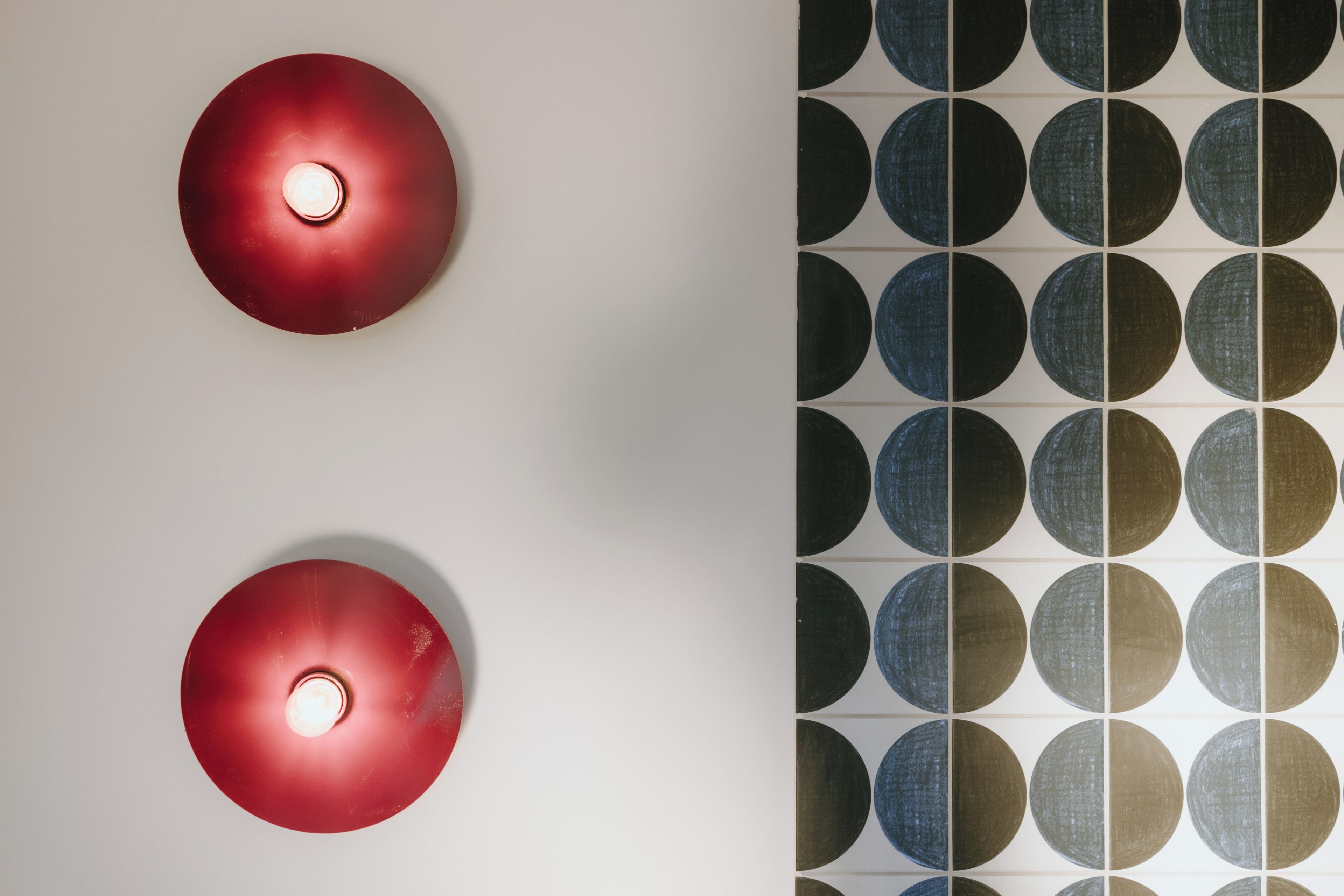 A wall with two circular light fixtures and a patterned wall design.