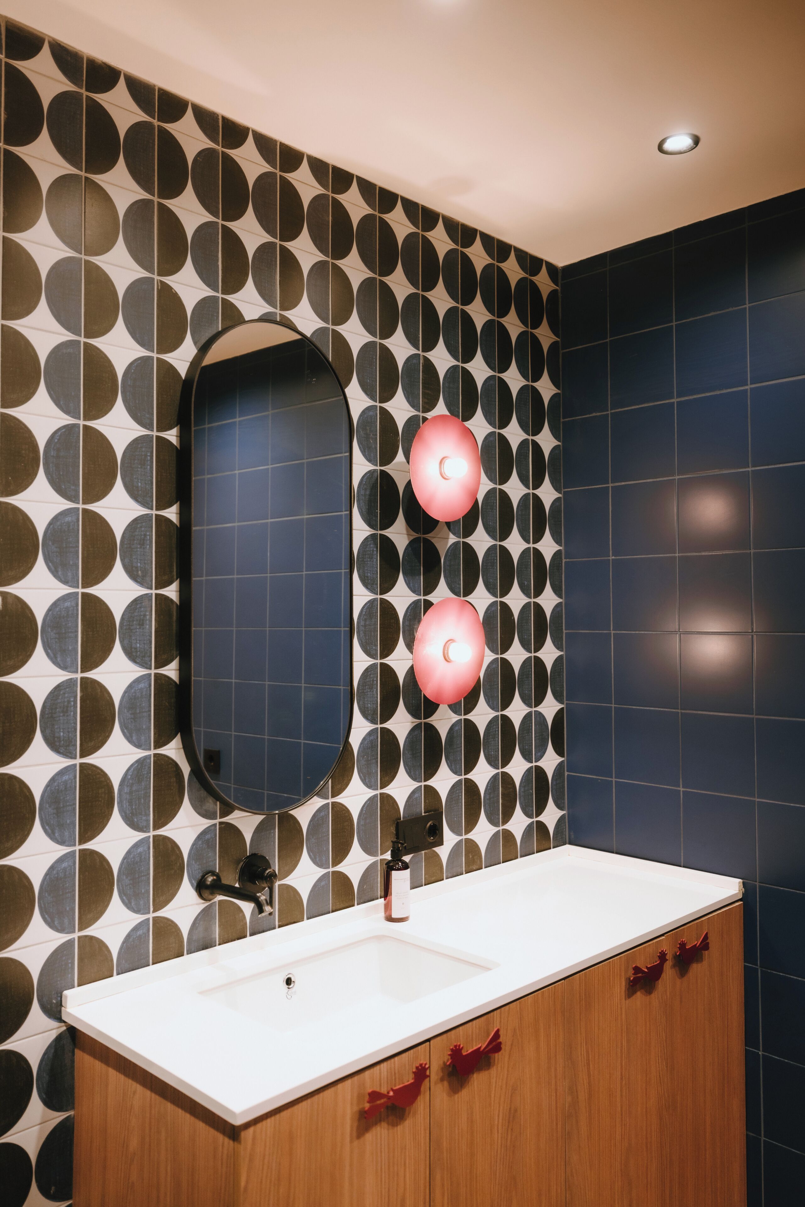 Ein Badezimmer im modernen Stil mit einem großen Spiegel, einem Waschbecken und zwei Wandleuchten.