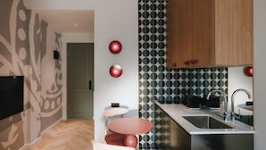 A modern kitchen with a herringbone floor, a built-in island with a sink, and a flat-screen TV mounted on the wall.