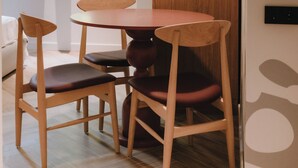 A dining area with a wooden table and chairs, a window with blinds, and a door with a wooden panel.