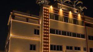 Un edificio de varios pisos con franjas verticales iluminadas, un garaje y motocicletas estacionadas.