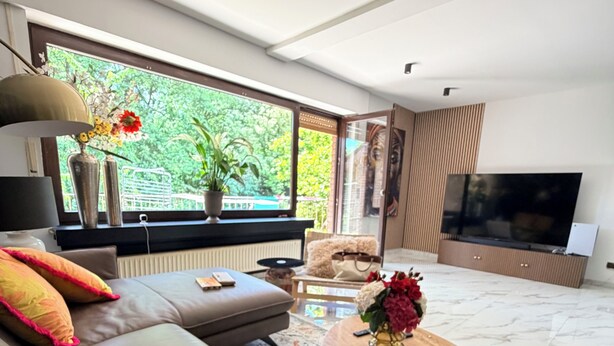 Ein modernes Wohnzimmer mit einer Couch, einem Couchtisch und einem Fernseher.