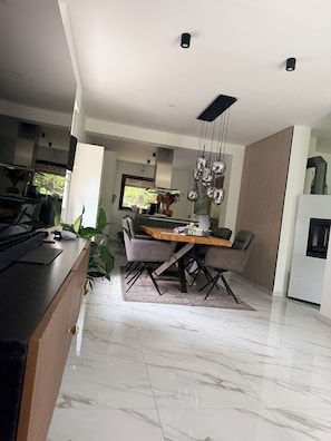 A modern kitchen with a dining area, marble flooring, and contemporary furniture.