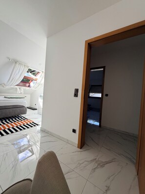 A modern interior with a bed, a patterned rug, and a door leading to another room.