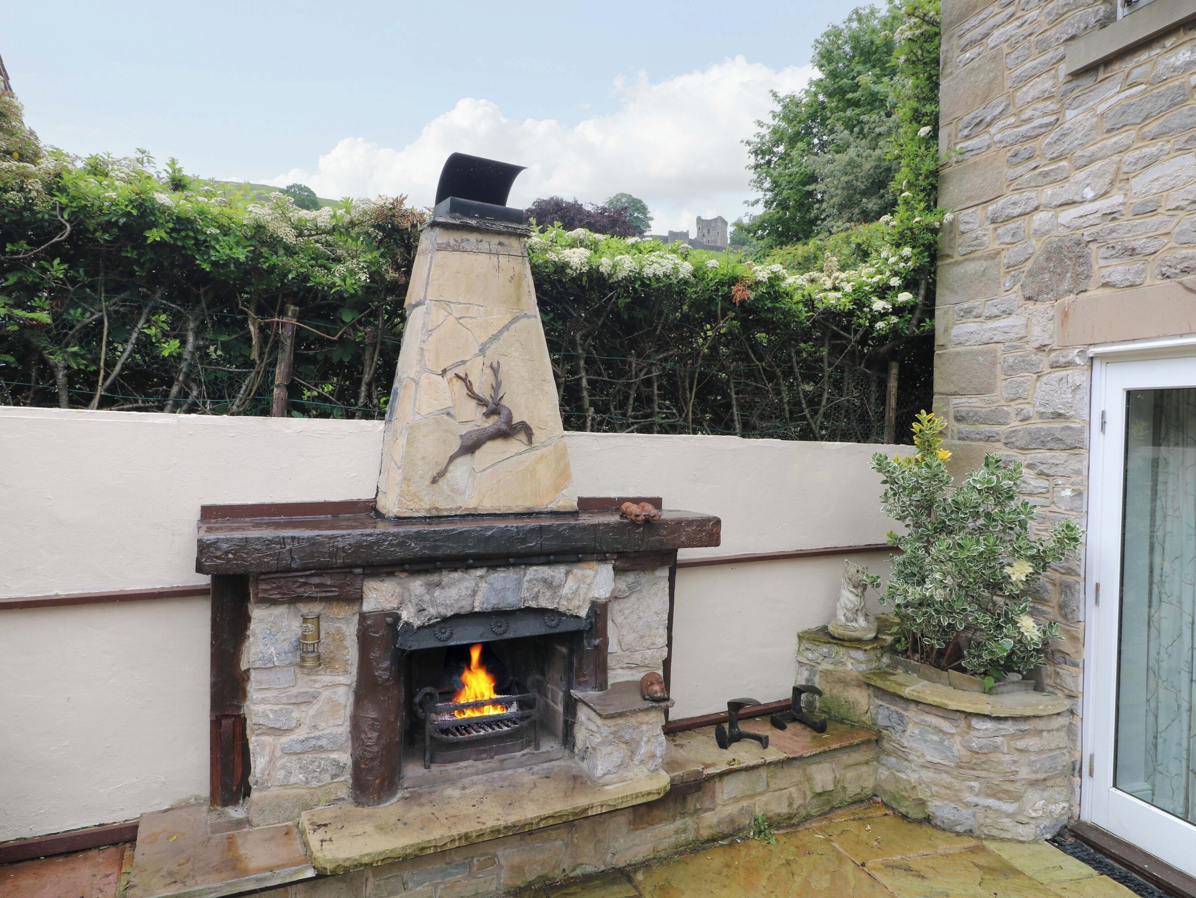 A stone fireplace with a fire, a stone chimney, and a stone wall.
