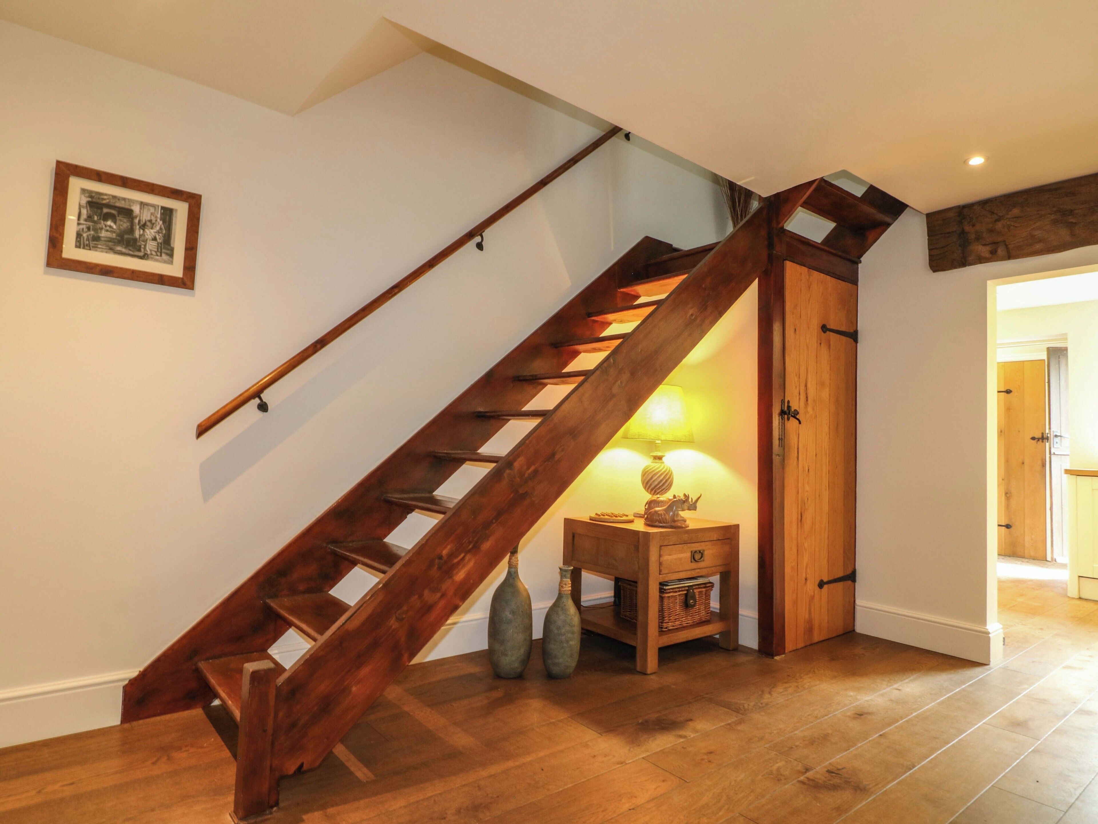 Un escalier en bois, avec une lampe et des objets décoratifs sur une table de chevet.